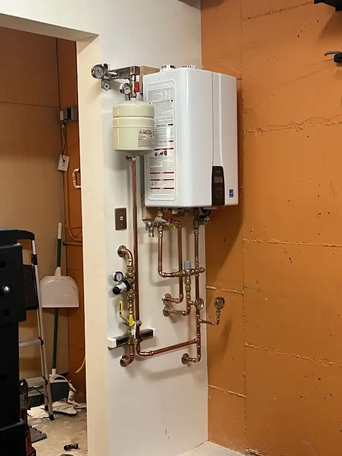 Plumbing technician inspecting water heater connections in DeForest